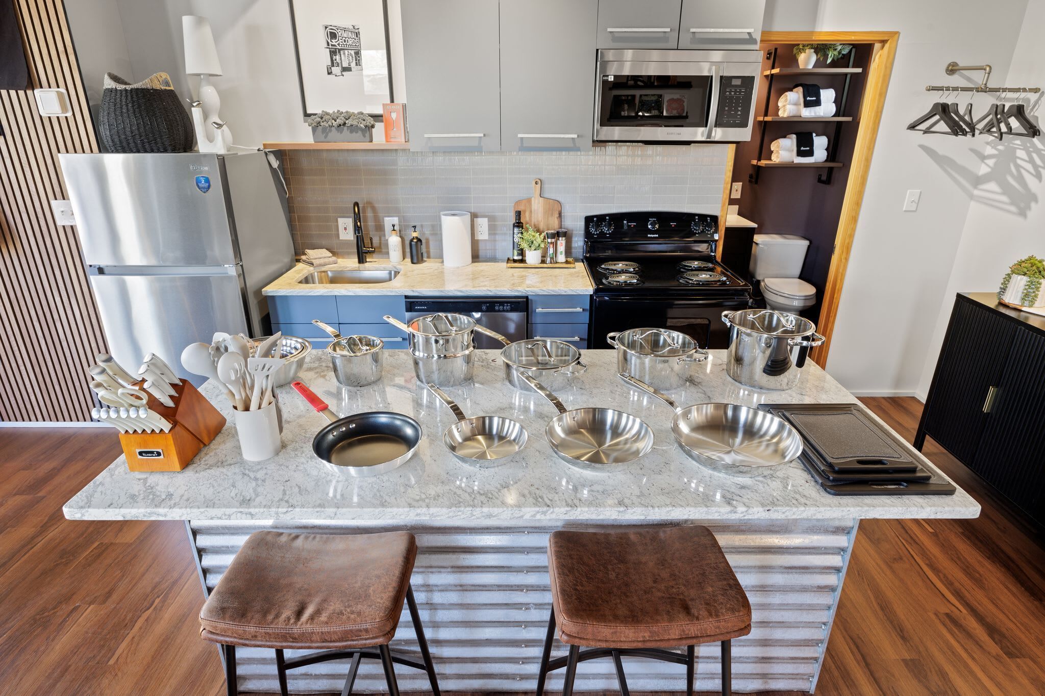 A modern kitchen with a central island, stainless steel appliances, and a wooden dining area.