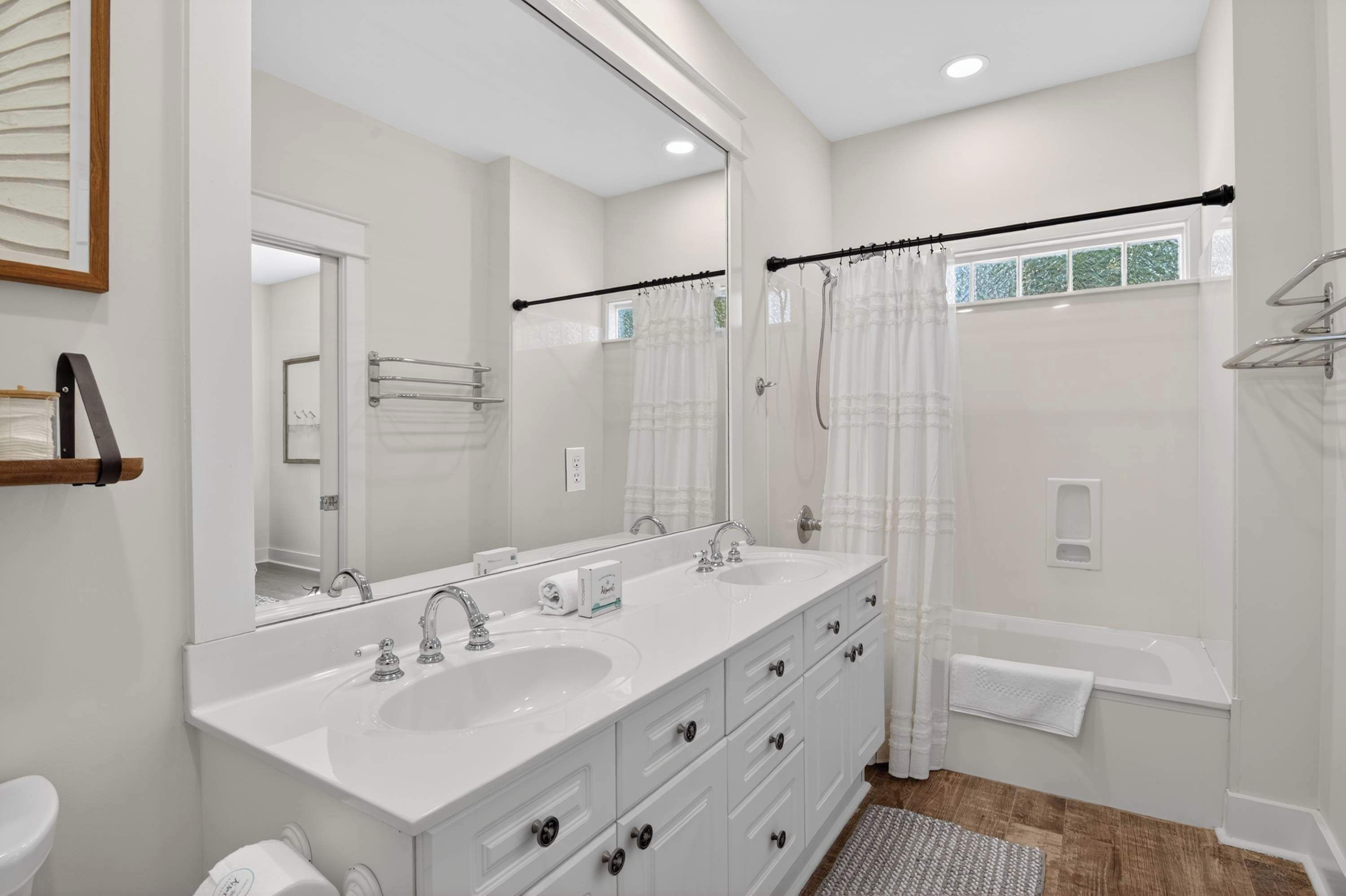 A modern bathroom with a double sink, a large mirror, a shower with a glass door, and a bathtub.
