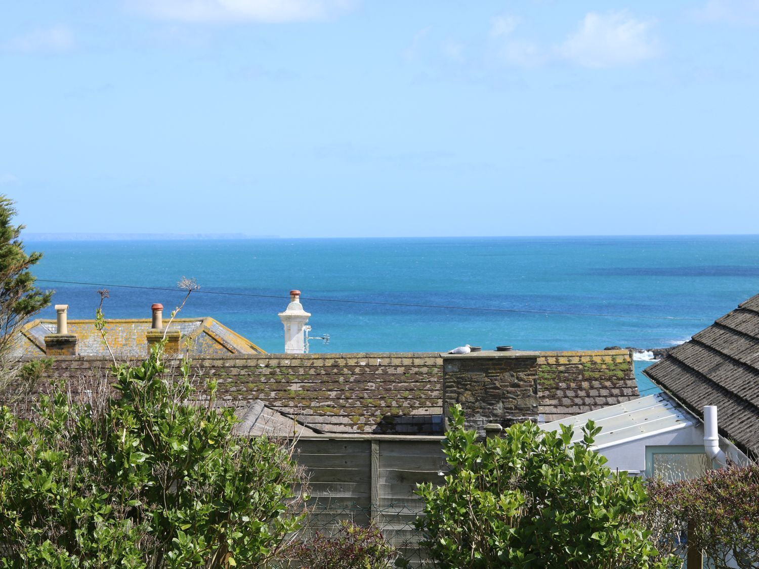 Paesaggio costiero con edifici in pietra, un faro e il mare.