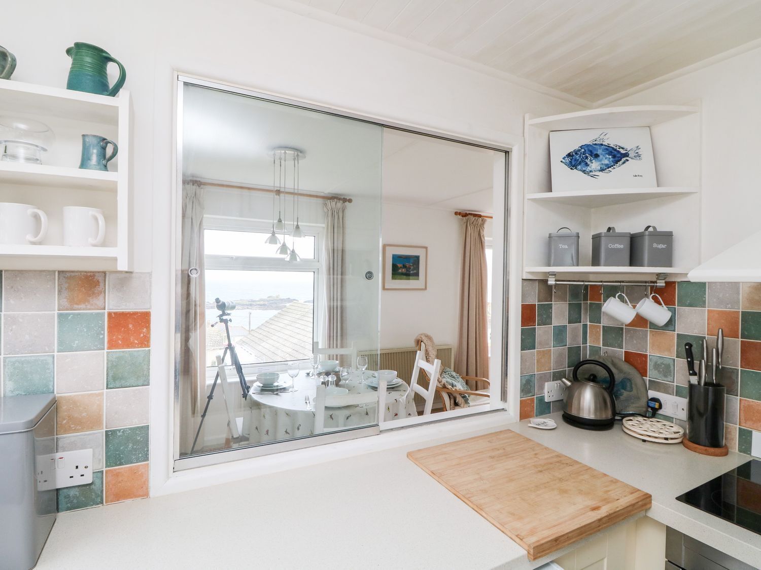 Een keuken met een groot raam, een eethoek en uitzicht op zee.