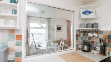 Een keuken met een groot raam, een eethoek en uitzicht op zee.