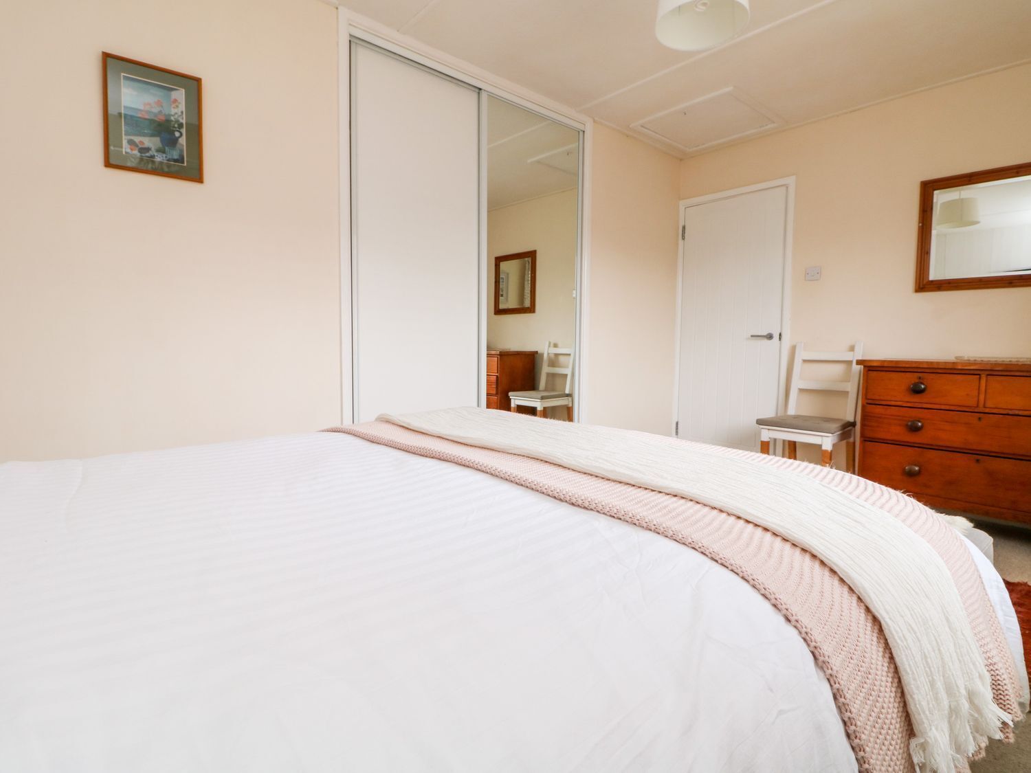 Un dormitorio con cama, cómoda, espejo y puerta que da a otra habitación.