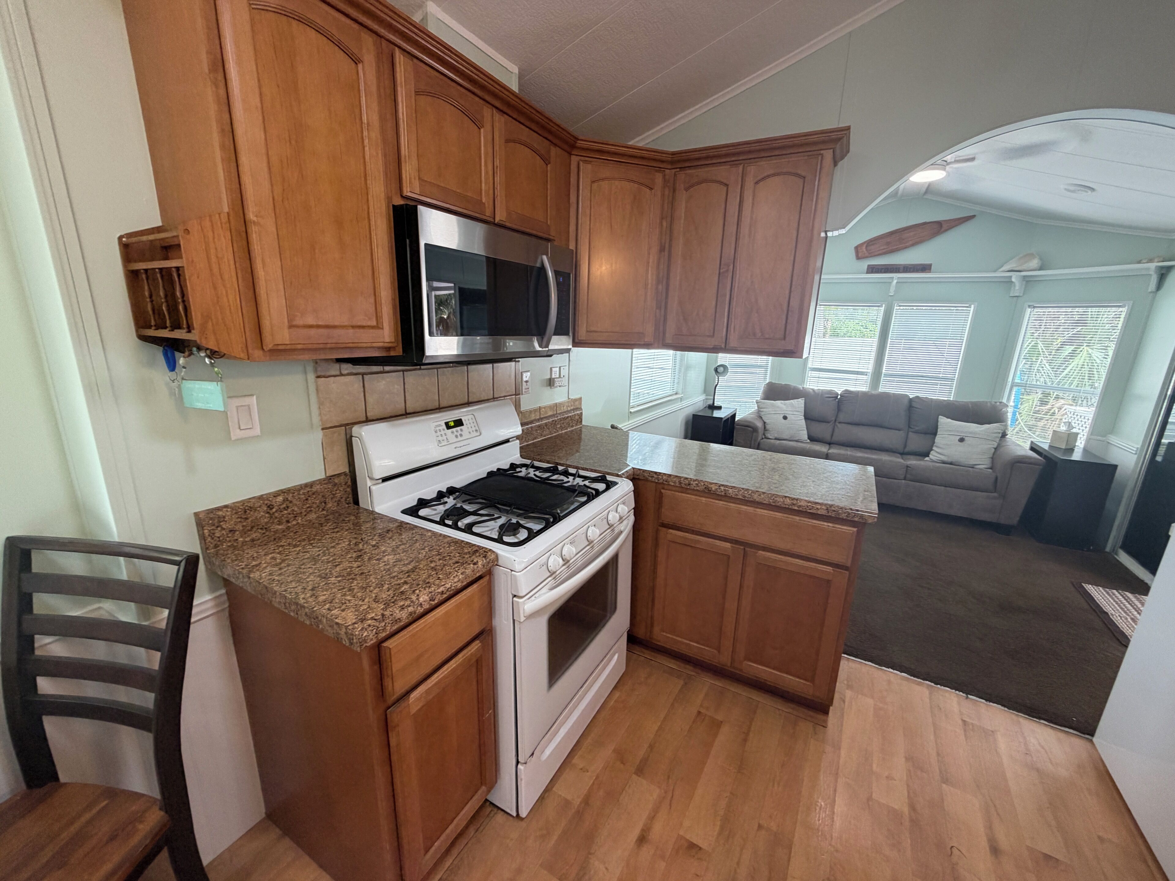 A compact kitchen with wooden cabinets, a gas stove, a microwave, and a built-in oven.