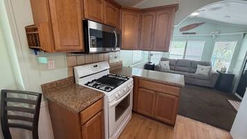 A compact kitchen with wooden cabinets, a gas stove, a microwave, and a built-in oven.