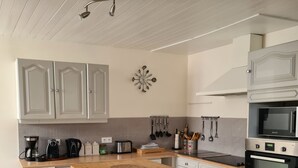 Uma cozinha moderna com banquetas de madeira, armários brancos, uma cafeteira, uma torradeira e um micro-ondas.