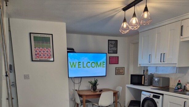 A modern living room with a sofa, a TV, a dining area, and a kitchen. - Private room in Little Bridgeford (Stafford)