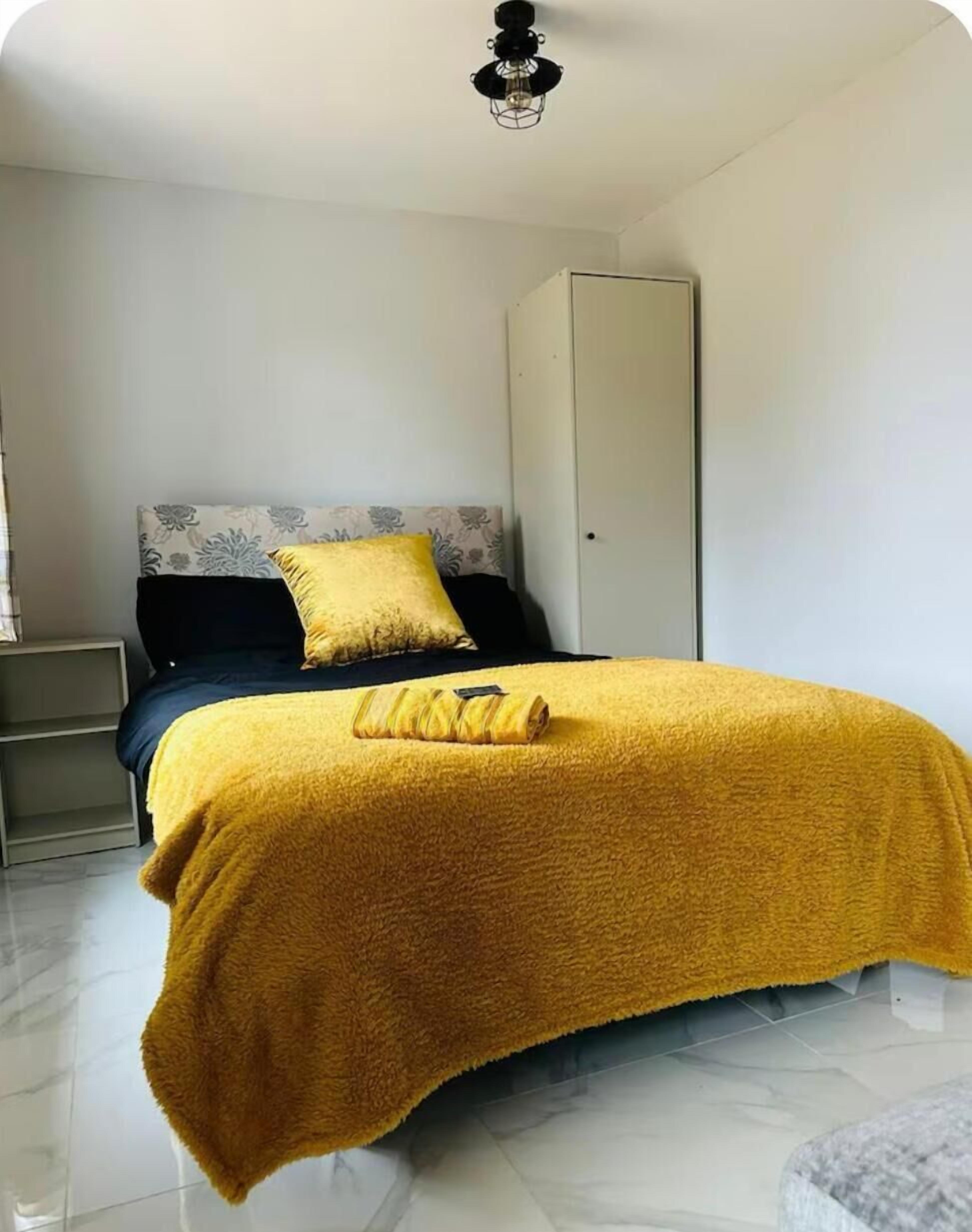 A bedroom with a bed, a wardrobe, a nightstand, and a bedside table.