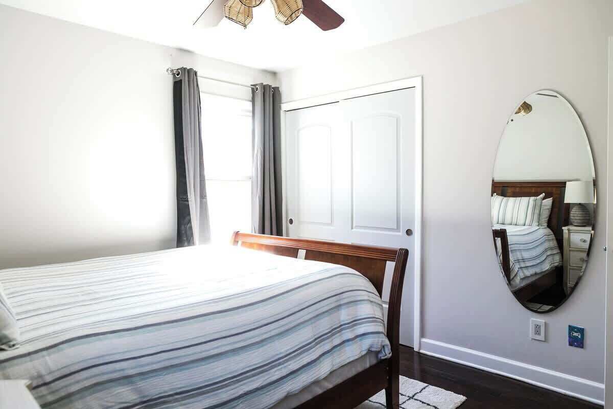 Une chambre à coucher avec un lit, une porte, un miroir et un ventilateur de plafond.