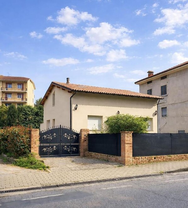 A two-story house with a tiled roof, a gated entrance, and a brick wall. - The Rose Cottage (Tavernelle)