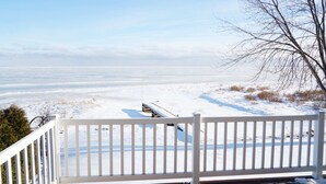 A snowy deck with a white railing overlooking a frozen landscape.