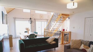 A spacious living area with a wooden staircase, a green sofa, and a grey sofa.