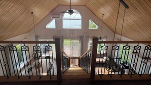 An attic room with wooden slats, a staircase, and a view of the outdoors.