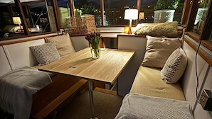 Un ambiente accogliente con un tavolo di legno, sedute imbottite e un vaso con fiori.