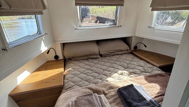 A compact bedroom with a bed, two windows with curtains, a small table, and a window seat. - Unique 2 Bed Waterside Retreat, Pet Friendly (Worcester)