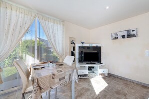 A dining area with a table, chairs, and a TV stand.