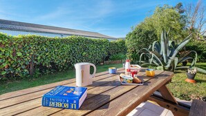 A wooden picnic table with a book, a mug, and food items.