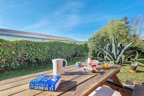 A wooden picnic table with a book, a mug, and food items.