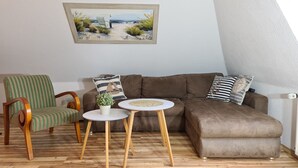 A living room with a brown sofa, striped armchair, and a small round table with a plant. - Apartment 'FeWo1' with Private Terrace and Wi-Fi (Oesterdeichstrich)