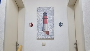 A staircase leading to a room with a painting of a lighthouse, a door, and a wall-mounted light fixture. - Apartment 'FeWo1' with Private Terrace and Wi-Fi (Oesterdeichstrich)