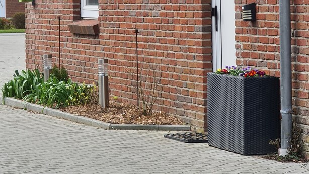 A brick building with a tiled roof, a white door, and a small garden area with plants. - Apartment 'FeWo1' with Private Terrace and Wi-Fi (Oesterdeichstrich)