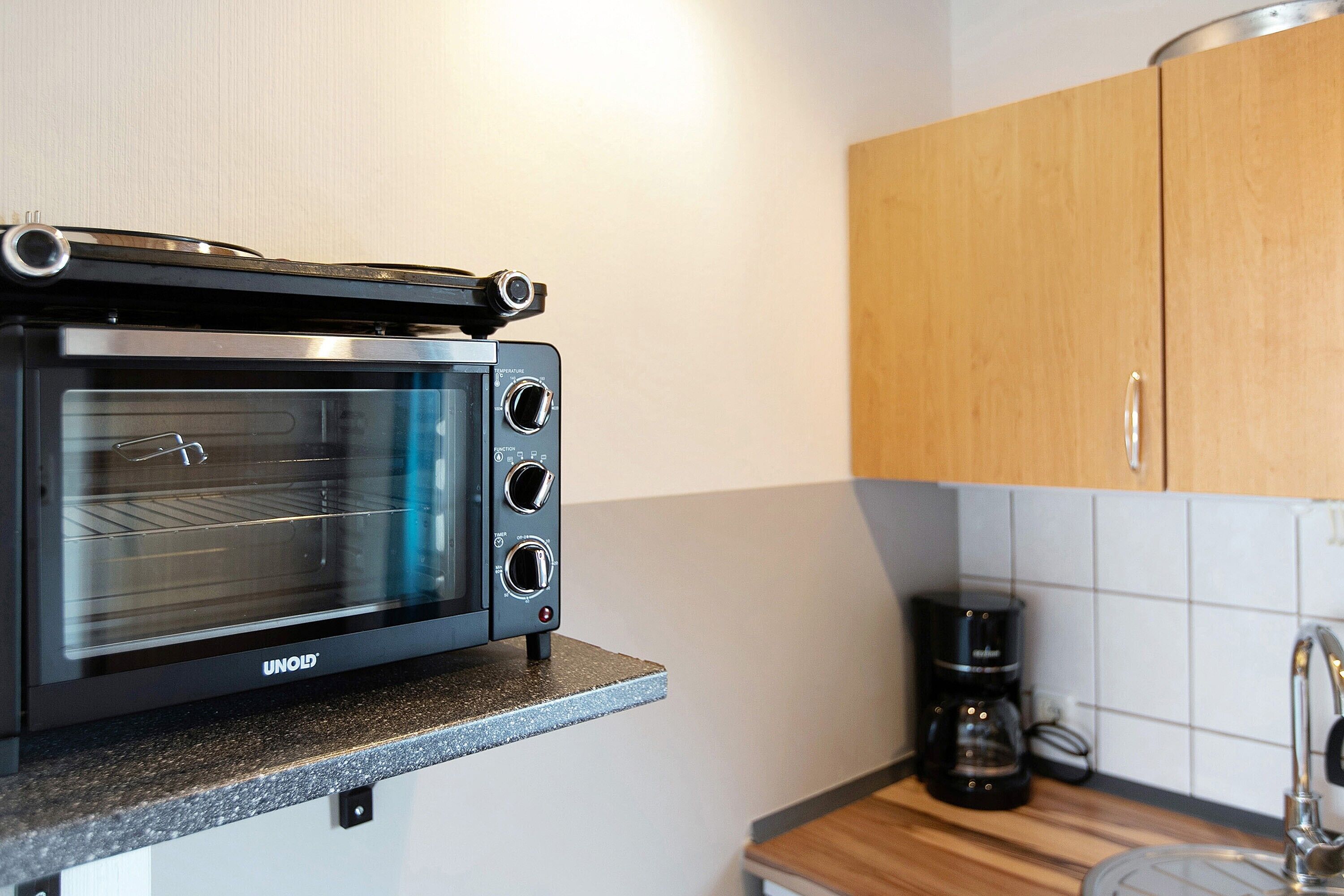 Una cucina con forno integrato, macchina da caffè e mobili in legno.