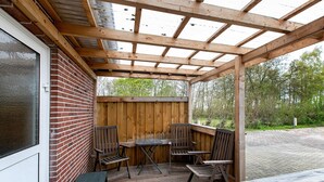 A covered patio with a brick wall, wooden ceiling, and outdoor seating. - Apartment 'FeWo2' with Wi-Fi (Oesterdeichstrich)