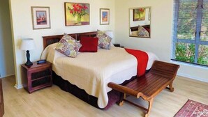 Un dormitorio con cama, mesitas de noche, un banco y obras de arte en las paredes.