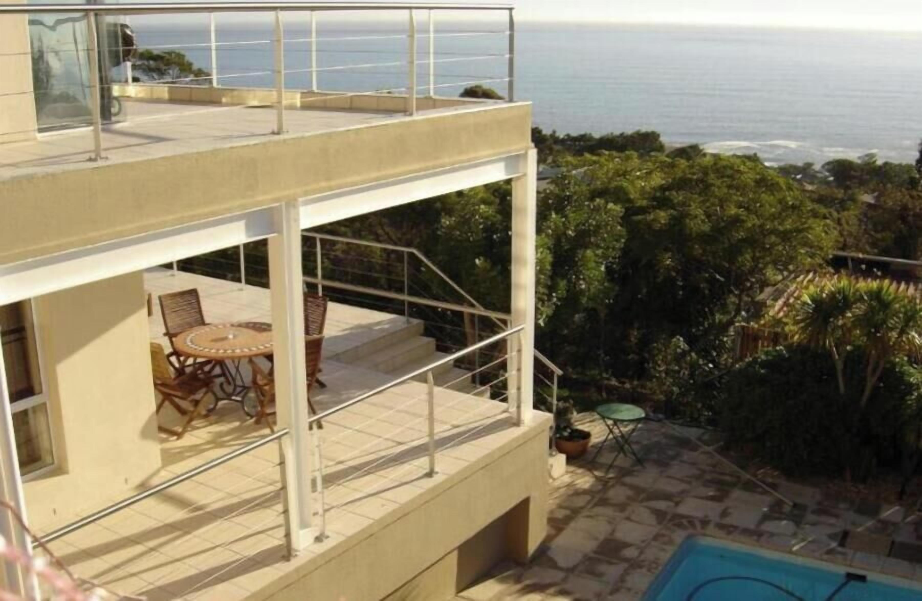 Ein zweistöckiges Gebäude mit Balkon, Sitzgelegenheiten im Freien und einem Pool.