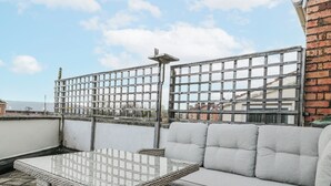 A rooftop terrace with a wicker table and grey cushioned seating. - The Flat House (Taunton)
