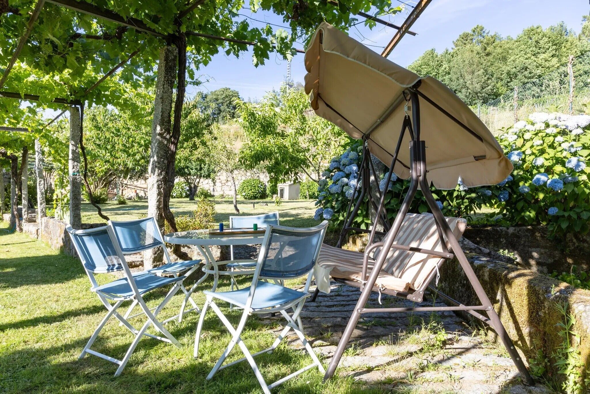A garden with a table and chairs, a swing, and a canopy.
