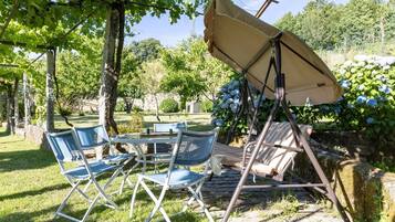 A garden with a table and chairs, a swing, and a canopy.