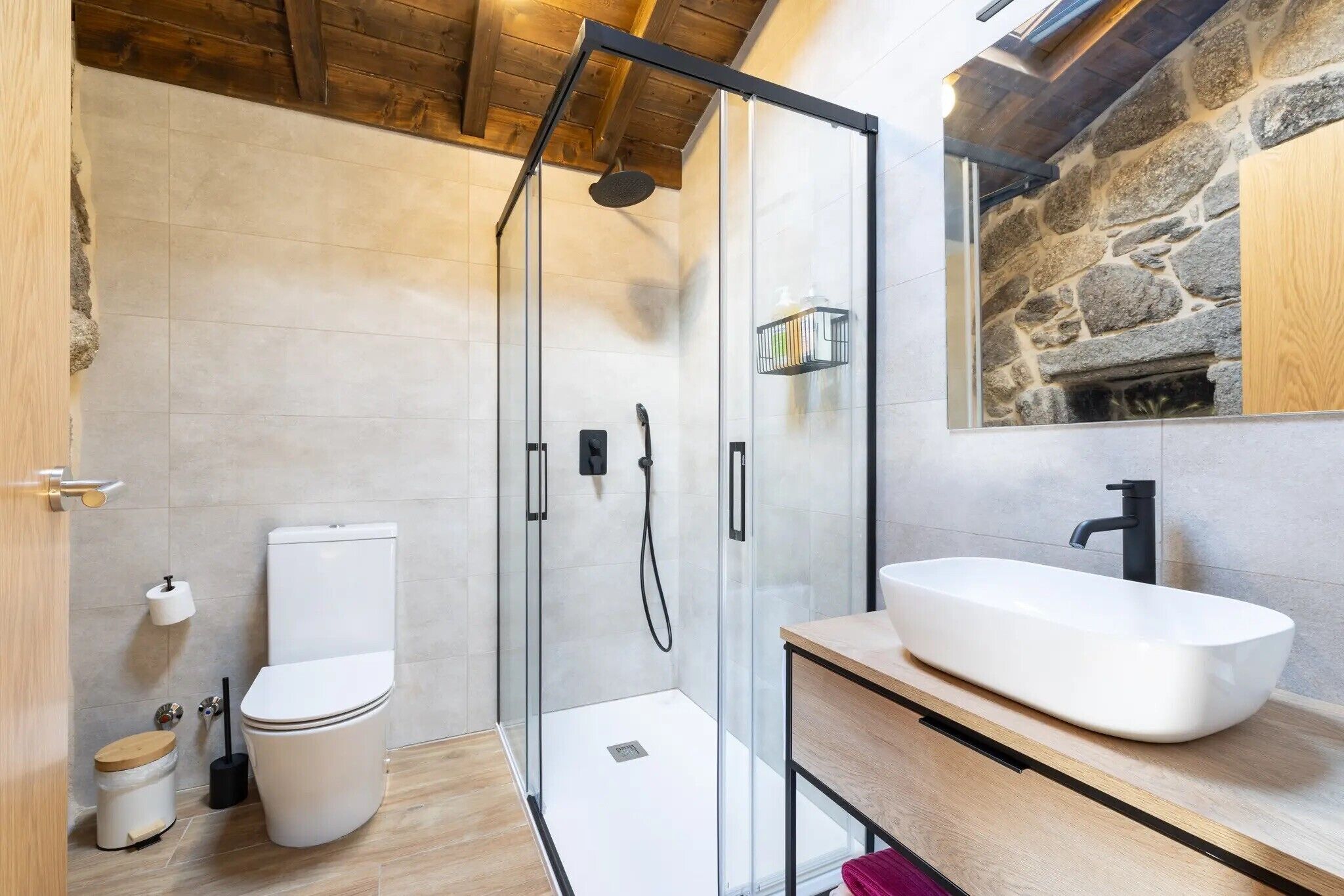 A modern bathroom with a glass-enclosed shower, a white toilet, and a large white sink.
