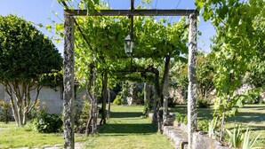 A garden pathway with a pergola structure, stone walls, and greenery. - CDC Casa do Capitán Leiro: Relax Among Vineyards and Forests in Ribeiro (Cubilledo)