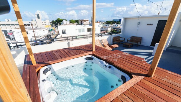 Un patio in legno con idromassaggio, sedute all'aperto e vista sulla città.