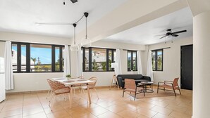 Un'ampia zona giorno con tavolo e sedie da pranzo, divano e ventilatore a soffitto.
