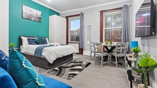 Quarto moderno com uma cama, escrivaninha e televisão.