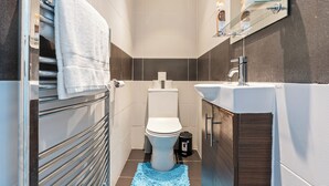 Um banheiro moderno com vaso sanitário, pia e porta-toalhas.