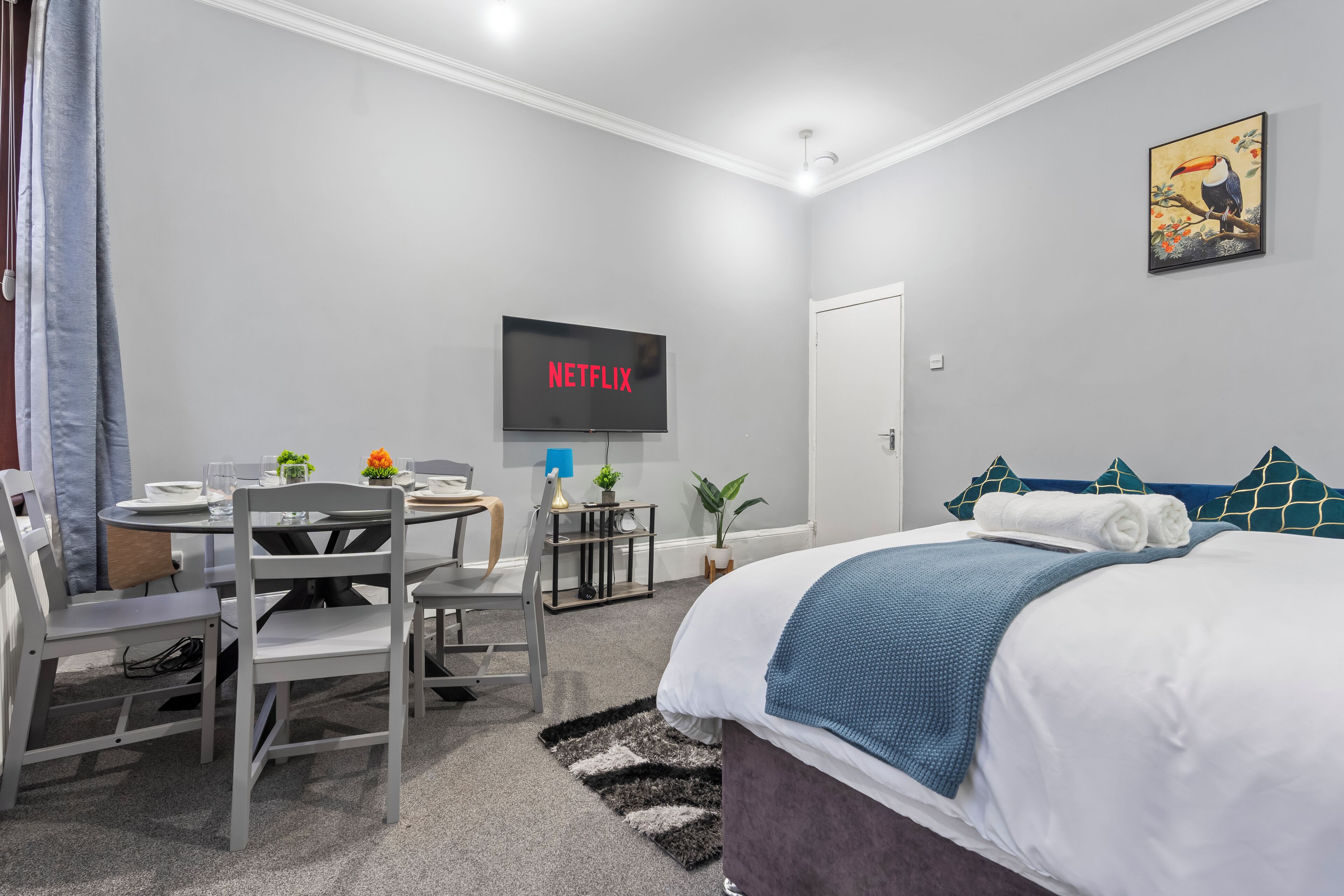 Une chambre d’hôtel avec un lit, un bureau avec des chaises, une télévision et une porte.
