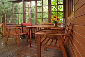 A wooden deck with a table and chairs, a red toolbox, a vase with sunflowers, and a lantern. - Holiday Home With a Fireplace and a Large Terrace (Choczewo)