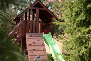A wooden play structure with a slide and climbing holds. - Holiday Home With a Fireplace and a Large Terrace (Choczewo)