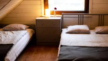 Un dormitorio con dos camas individuales, una mesita de noche con lámpara y una ventana con vistas a zonas verdes.