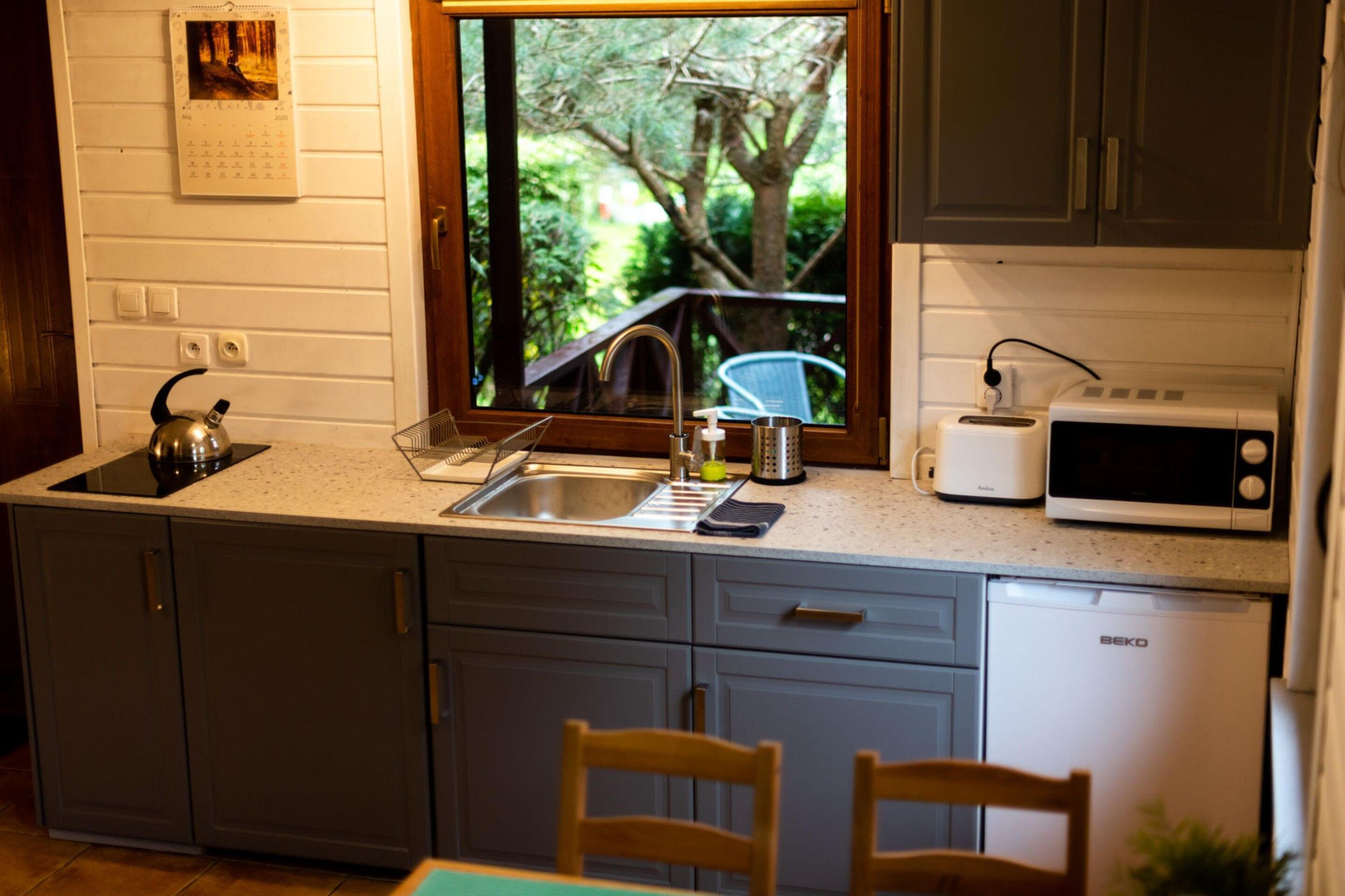 Una cocina con ventana, tetera, tostadora y pileta.