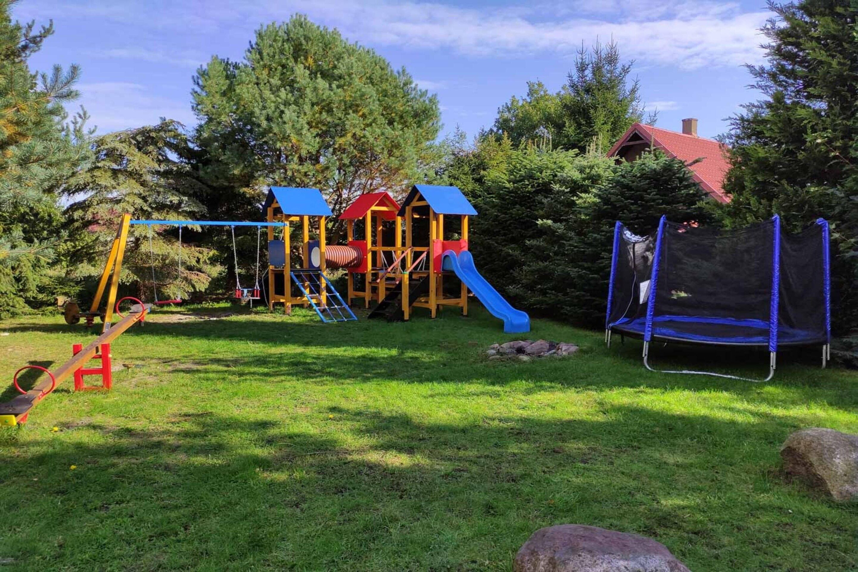A playground with a slide, swings, and a trampoline.