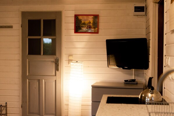 A room with a white door, a small table with a television, and a window with blinds. - Holiday Home With a Fireplace and a Large Terrace (Choczewo)