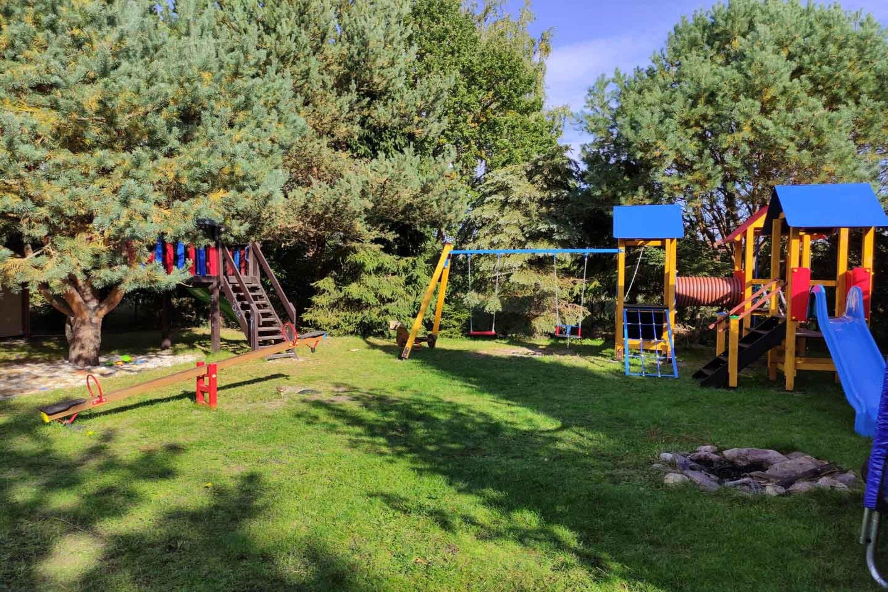 Un parque infantil con tobogán, columpios y una estructura para escalar.