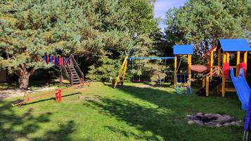 Un parque infantil con tobogán, columpios y una estructura para escalar.