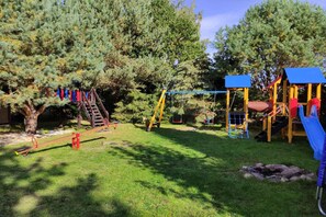 A playground with a slide, swings, and a climbing structure. - Holiday Home With a Fireplace and a Large Terrace (Choczewo)