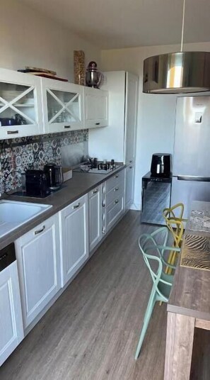 A kitchen with white cabinets, a microwave, a coffee maker, and a refrigerator. - 2-bedroom family apartment with large terrace and sea view (Bastia)