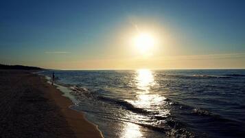 A beach with a clear sky and the sun reflecting on the water.