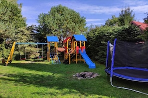 A playground with a slide, swings, and a trampoline. - Holiday Home With Fireplace and Large Terrace (Choczewo)